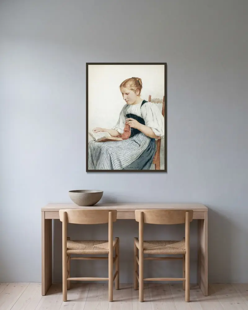 Stickande läsande flicka av Albert Anker inramad på en vägg