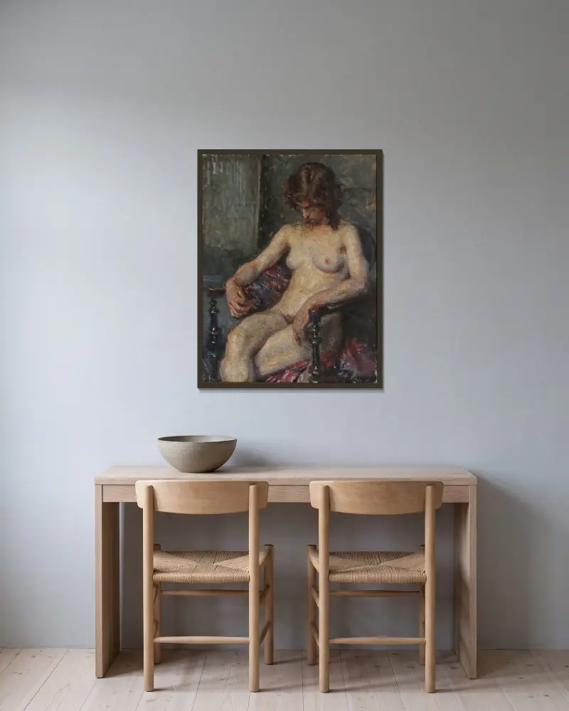 En nøgen kvindelig model siddende på en stol av Viggo Johansen inramad på en vägg